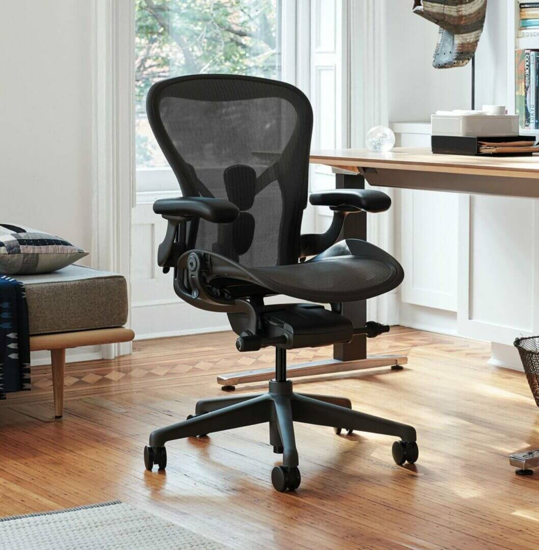 Ergonomic office chair with mesh back in modern home office, wooden floor, natural light through window.